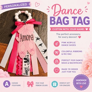 May include: A personalized dance bag tag featuring a pink acrylic ballet shoe charm with the name Amora printed on it. The charm is attached to a white beaded ring with multiple hanging ribbons in shades of pink, white, and black with dance motifs.