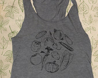 May include: Gray tank top with a black line drawing of various vegetables, including a pumpkin, onion, cucumber, and peppers. The text "made in USA, organic, baby, youth, adult sizes" is printed on the bottom of the tank top.