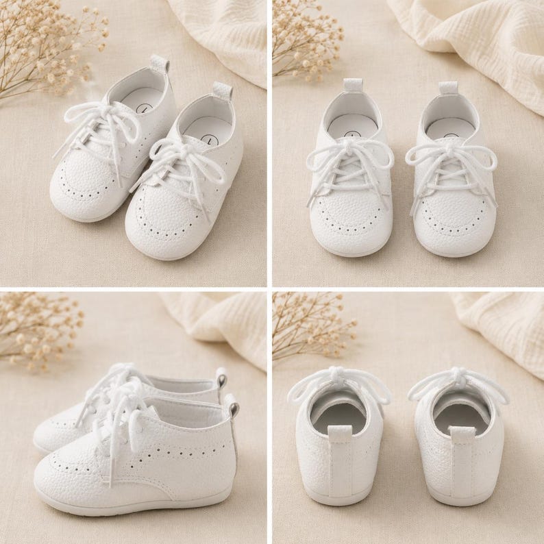 May include: A pair of white baby shoes with a textured pebble-grain finish, featuring a rounded toe, lace-up closure with white laces, and decorative perforated brogue detailing along the toe cap and sides, with a small pull tab at the heel.