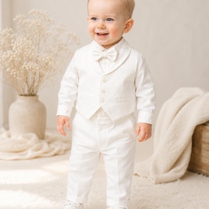 May include: A formal outfit consisting of a long-sleeved white button-down shirt, a matching white vest with three buttons, a white bow tie, and white trousers. The ensemble is completed with a pair of white lace-up dress shoes.