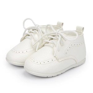 K&ouml;nnte beinhalten: Ein Paar wei&szlig;e Babyschuhe mit strukturiertem Leder-Aussehen. Die Schuhe haben ein klassisches Schn&uuml;rdesign und dekorative Perforationen. Die Schuhe sind f&uuml;r S&auml;uglinge konzipiert.