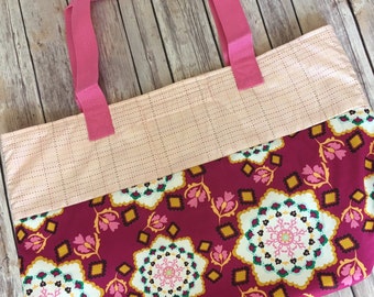 May include: A pink and red tote bag with a floral pattern. The bag has two pink handles and a pink and white checkered pattern on the top half.