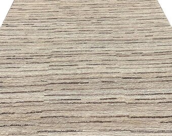 Peut inclure: Un tapis rectangulaire présentant un motif à rayures horizontales dans des tons beige, crème et brun foncé. Le design se compose de fines lignes irrégulières qui créent un aspect texturé sur toute la surface du revêtement de sol.