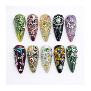 Uñas postizas estilo gótico con efecto de goteo y gemas, set de uñas con diamantes de imitación cromados de fantasía, uñas con cristales negros, verdes y morados, uñas almendradas pintadas a mano de lujo.