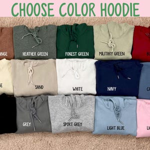 May include: A selection of hoodies in various colors, including heather orange, forest green, and light pink. Each hoodie has a drawstring and is labeled with its color name. The text "CHOOSE COLOR HOODIE" is at the top.