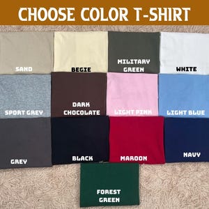 May include: A selection of folded t-shirts in various colors, including sand, beige, military green, and white. The image displays the text "CHOOSE COLOR T-SHIRT" at the top, with each shirt labeled with its color name.