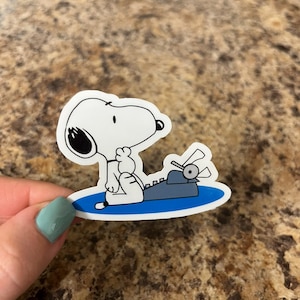 Snoopy Writing Typewriter Sticker – Funny Cartoon Dog Vinyl Sticker for Writers, Book Lovers, and Peanuts Fans – 2.5"x2" Waterproof