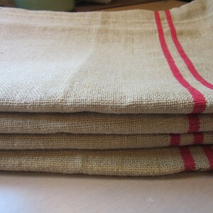 May include: A stack of four linen tea towels with red stripes. The towels are folded and have a rustic, farmhouse style.