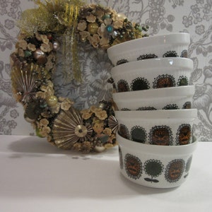 May include: A stack of five white ceramic bowls with a black and brown floral pattern. The bowls are stacked on a white surface.