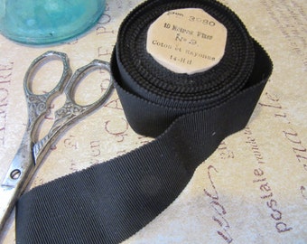 Puede incluir: Un rollo de cinta de grosgrain negro con una etiqueta que dice "Pon 3980 10 Metres Fires No. 9. Coton et Rayonne 14-HH".
