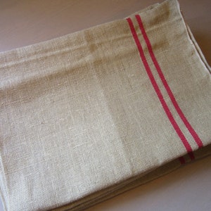 May include: A stack of natural linen tea towels with two red stripes.