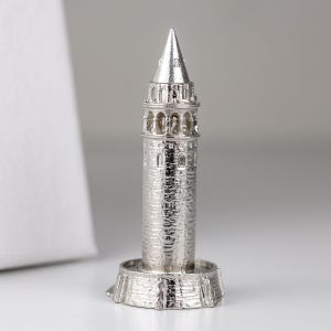 Polished stainless steel miniature of the Galata Tower on a round base against a light gray background