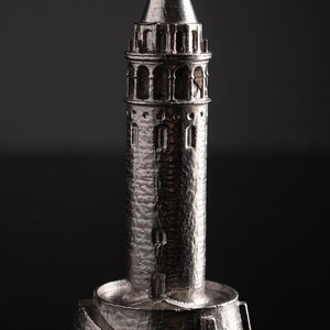 Close view of the polished Galata Tower miniature showing the arched windows and stone texture against a black background
