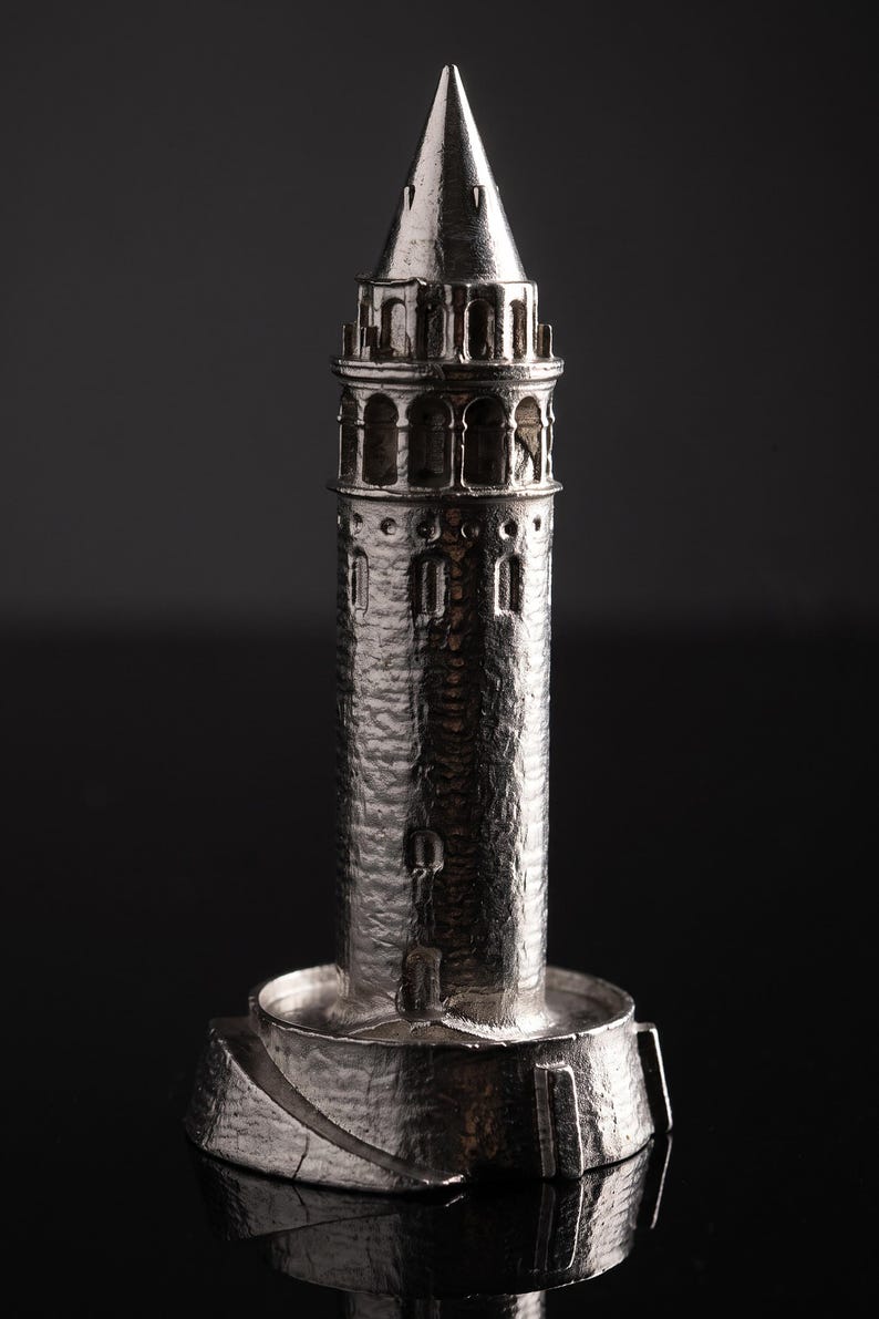 Close view of the polished Galata Tower miniature showing the arched windows and stone texture against a black background