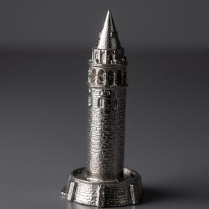 Polished Galata Tower miniature seen from a slight angle on a reflective dark gray surface