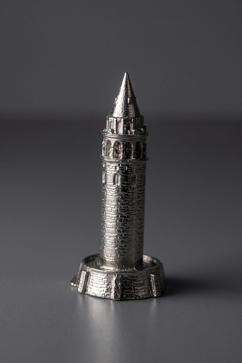 Polished Galata Tower miniature seen from a slight angle on a reflective dark gray surface