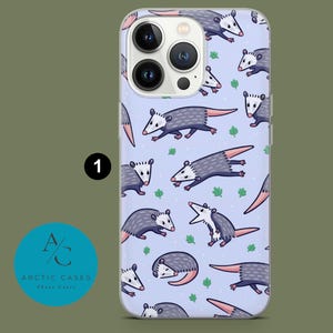 May include: A clear phone case with a light blue background and a repeating pattern of cartoon opossums. The opossums are in various poses, some are curled up, some are standing on their hind legs, and some are walking. The case has a white border and a clear back.