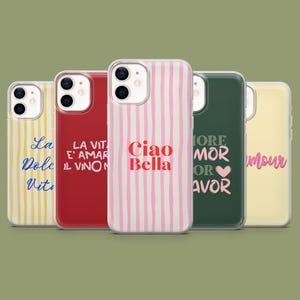 Op de afbeelding: Een verzameling van vijf telefoonhoesjes met verschillende ontwerpen en kleuren. Eén hoesje heeft roze en witte verticale strepen met de tekst "Ciao Bella". Andere hoesjes tonen zinnen als "La Dolce Vita" en "More Amor or Favor."