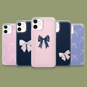 May include: Four different phone cases with a clear background. The cases are all for the iPhone 13 Pro Max. The cases are all different colors and have different designs. One case is pink with a black bow, one is blue with a pink bow, one is pink with white bows, and one is purple with pink bows.