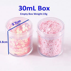 May include: Two clear plastic jars filled with pink sequins. The jars are labeled "30ml Box" and measure 4.8cm in height and 3.7cm in diameter. The empty box weight is 19g. The sequins are small and round.
