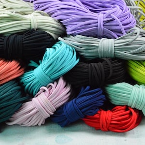 May include: A collection of colorful elastic cords in various hues, including black, teal, red, purple, and green. The cords are bundled and tied, showcasing a variety of shades and textures. Ideal for crafting and DIY projects.