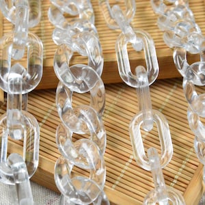 Könnte beinhalten: Nahaufnahme einer durchsichtigen Plastikkette. Die Kette besteht aus ovalen Gliedern und liegt auf einer geflochtenen Bambusoberfläche.