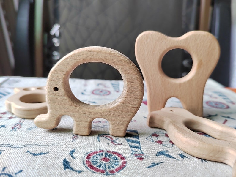 May include: Three wooden teethers shaped like an elephant, a tooth, and a bird. The teethers are made of natural wood and are designed for babies to chew on.