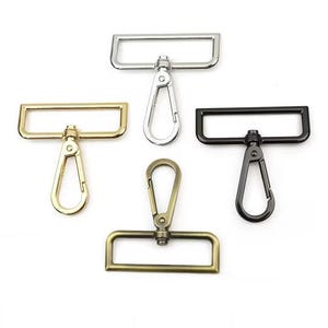 May include: Five metal swivel clasps in silver, gold, and black. Each clasp has a rectangular loop and a lobster claw clasp. The clasps are designed for use in bags, straps, and other crafting projects.
