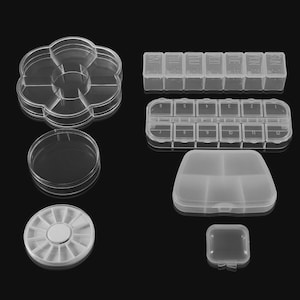 May include: A selection of clear plastic storage containers. The image shows a flower-shaped tray, round containers, a weekly pill organiser, and a small square container. These are designed for organising small items.
