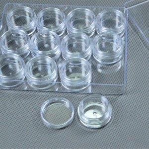 May include: A clear plastic container with a lid, holding twelve small, round, transparent jars. Two additional jars are outside the container. The jars are designed for storing small items, such as cosmetics or craft supplies.