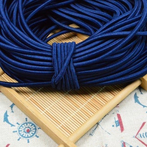 May include: A large spool of dark blue elastic cord. The cord is wound tightly and is ready to be used for crafting projects.