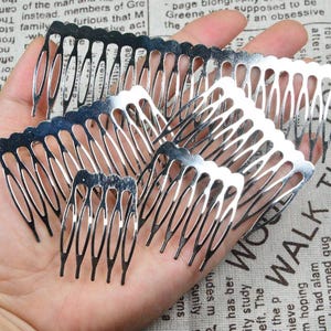May include: Several silver-coloured hair combs of different sizes. The combs feature an openwork design with multiple tines. The image shows the combs held in a hand, suggesting they are for hair styling or as accessories.