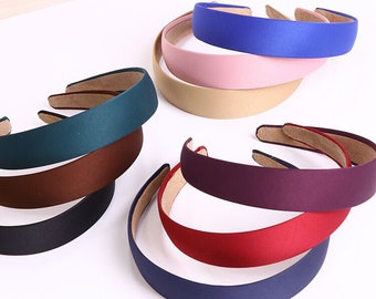 May include: A set of eight wide, fabric-covered headbands in various colors, including navy blue, dark blue, red, purple, brown, teal, beige, and pink.