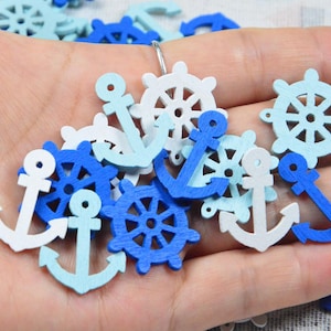 May include: A collection of small, flat wooden embellishments shaped like nautical anchors and ship steering wheels. The pieces are painted in various shades of blue and white, featuring cut-out details throughout each individual shape.