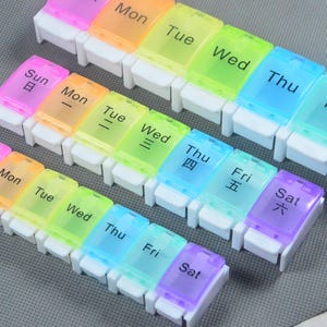 Puede incluir: Tres pastilleros semanales coloridos. Cada pastillero tiene siete compartimentos, uno para cada día de la semana, etiquetados con los días de la semana en inglés y chino. Las tapas son translúcidas y vienen en colores del arcoíris.