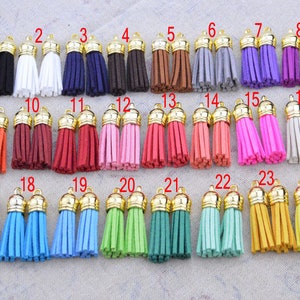 May include: Twenty-four pairs of small, colorful tassels with gold metal tops. The tassels are arranged in four rows of six pairs each.
