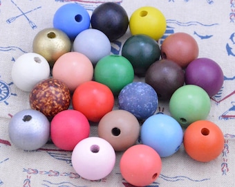 May include: A collection of wooden beads in various colors and finishes, including natural wood, painted, and metallic. The beads are round and have a hole in the center for stringing.
