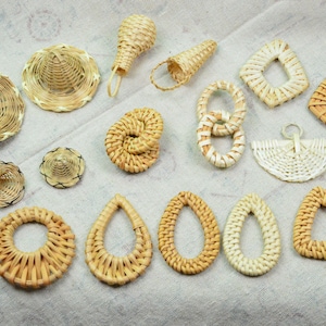 May include: A collection of 15 woven wicker and rattan earrings in various shapes, including circles, ovals, triangles, and a fan shape. The earrings are all natural in colour and have a rustic, handmade look.