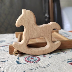 May include: A wooden rocking horse toy, made of light brown wood, with a simple design. The horse is sitting on a bamboo tray.