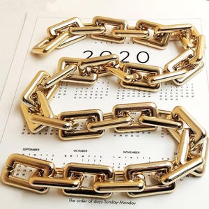 Può includere: Una collana a catena dorata con maglie rettangolari, disposta a forma curva. La collana è esposta su una pagina di calendario con l'anno 2020 visibile. Il calendario mostra i mesi di settembre, ottobre e novembre.