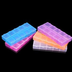 May include: A set of four rectangular plastic storage organisers, each featuring ten individual compartments with hinged lids. The containers are translucent and come in vibrant shades of blue, pink, orange, and purple, arranged in a stacked formation.