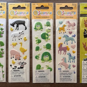 Può includere: Cinque confezioni verticali di adesivi gonfi Sandylion. I fogli presentano vari disegni, tra cui draghi verdi, animali da fattoria come mucche e maiali, tartarughe verdi, cavalli colorati con cuori e animali del bosco come cervi e volpi.