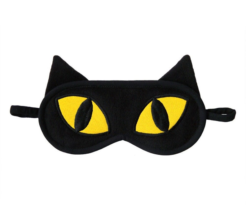 May include: Black sleep mask with yellow cat eyes.