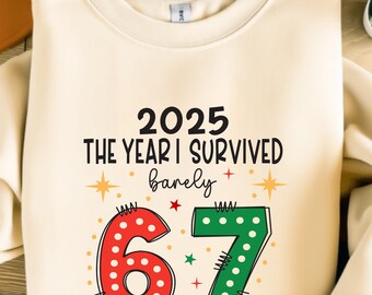 Peut inclure: Sweat-shirt crème avec le texte "2025 THE YEAR I SURVIVED barely" en noir. En dessous, les chiffres "67" en rouge et vert avec des accents décoratifs. Un design amusant et festif.