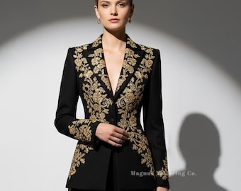 May include: A black suit with gold floral embroidery. The jacket has a V-neck and the pants are straight-legged. The embroidery is on the lapels, cuffs, and down the sides of the pants. The text "Magnus Wedding Co." is visible on the jacket.