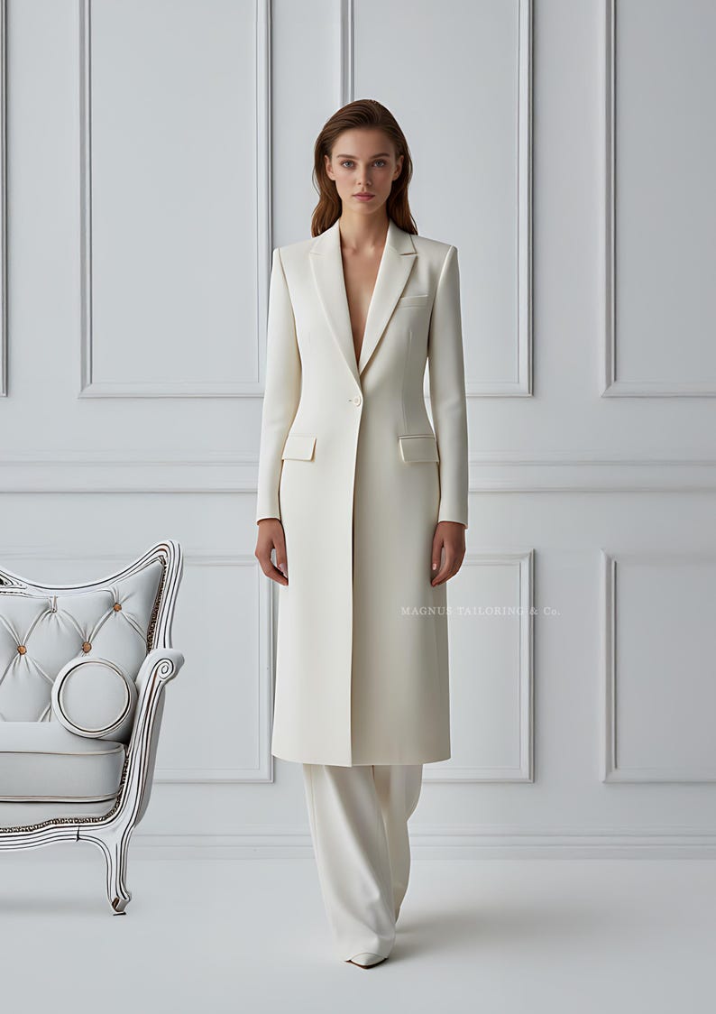 Front view of women’s ivory long tailored coat and wide-leg pants in minimalist studio