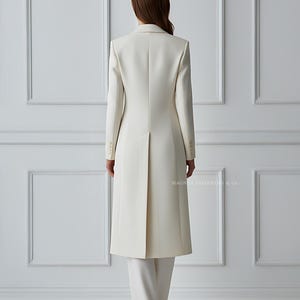 Back view of ivory coat suit highlighting vent and long silhouette