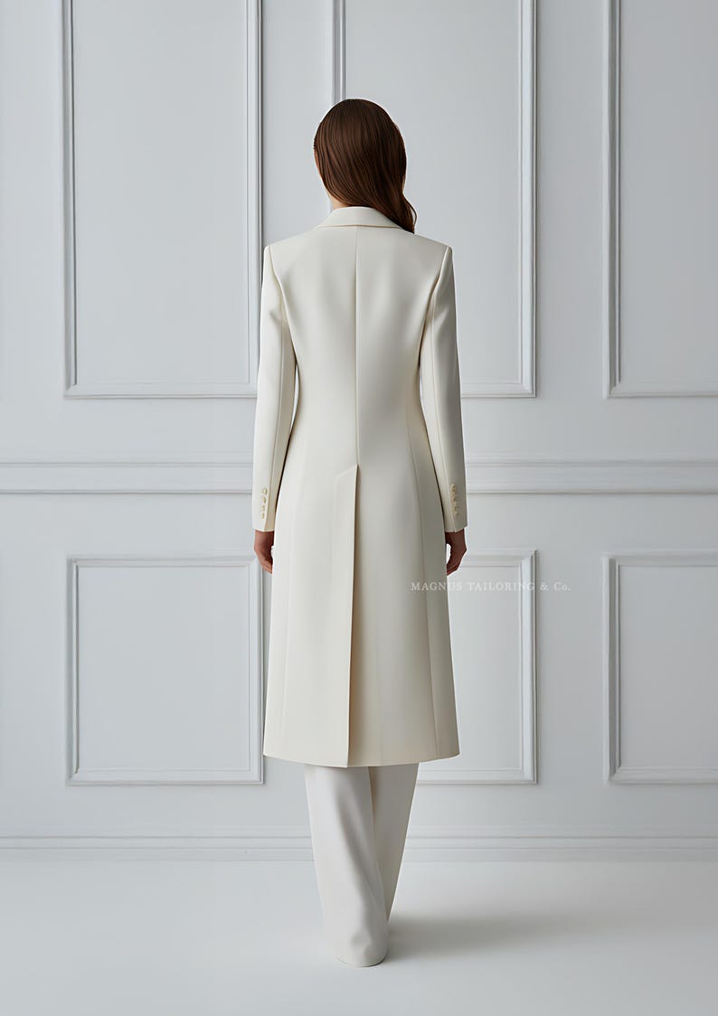 Back view of ivory coat suit highlighting vent and long silhouette