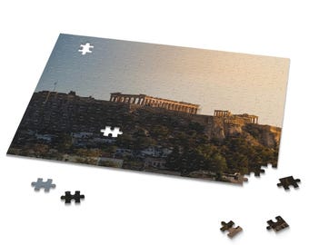 Könnte beinhalten: Ein teilweise zusammengesetztes Puzzle mit einer malerischen Ansicht der Akropolis in Athen, Griechenland. Das Puzzle zeigt die antiken Ruinen auf einem Hügel, mit blauem Himmel und goldenem Sonnenlicht. Mehrere Puzzleteile liegen verstreut.