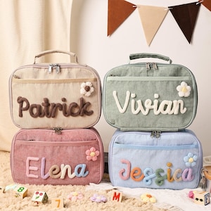 May include: Four corduroy lunch bags in beige, green, pink, and blue, each with a name in a contrasting color. Each bag has a small flower and a handle. The names are Patrick, Vivian, Elena, and Jessica.